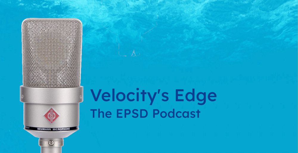 A Neumann TLM 103 microphone in front of a row of records to illustrate recording the Velocity's Edge podcast